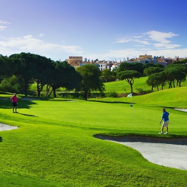 Golfer on Vale do Lobo Golf course with resort accommodation in the background